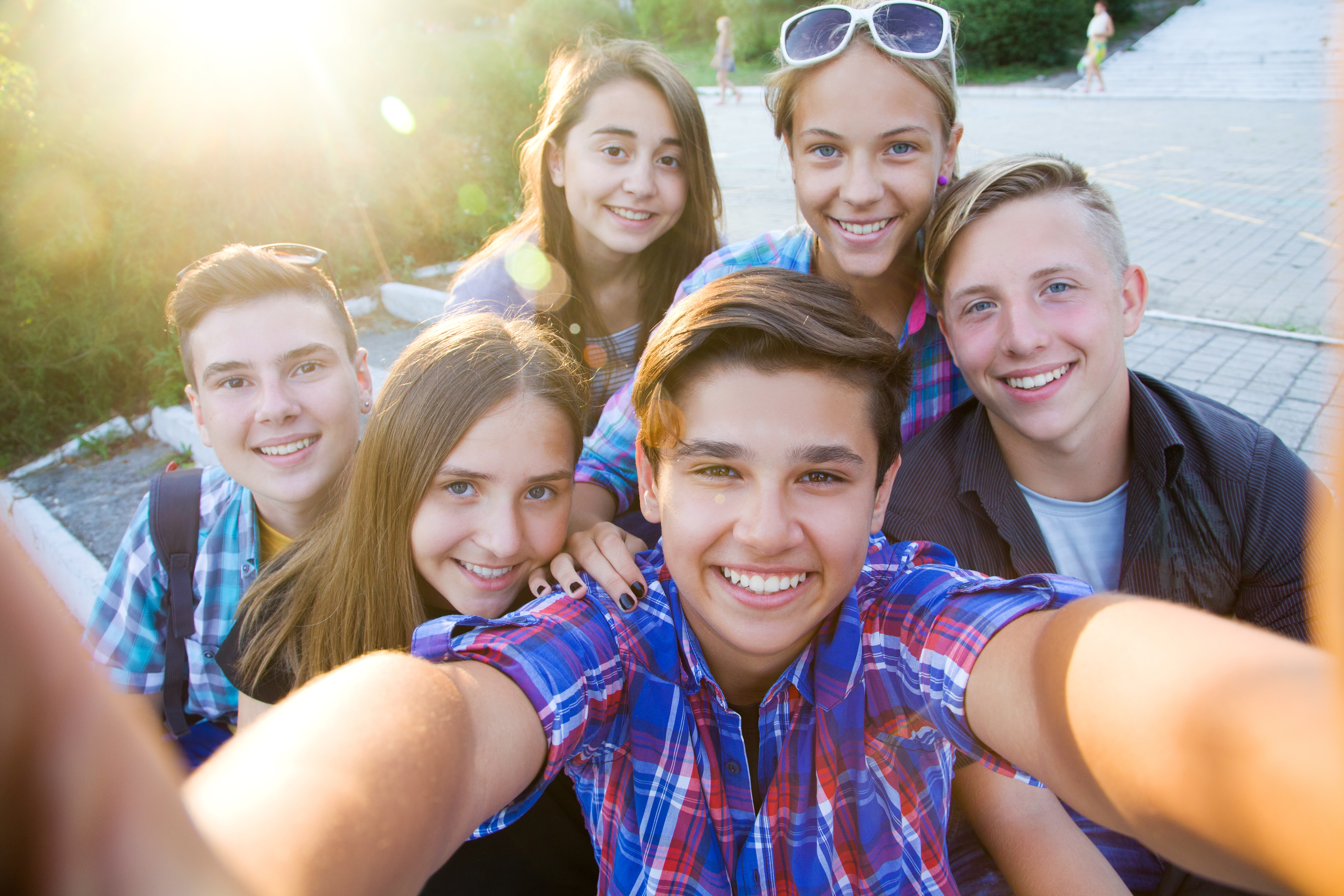group of smiling teenagers in the park taking a selfie